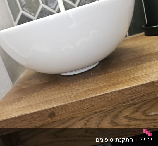 כיור לבן עם ברז מים על רקע אריחים